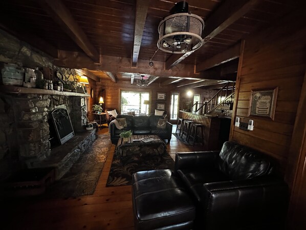 Een gezellig chalet interieur met een stenen openhaard, lederen meubels en een houten plafond.