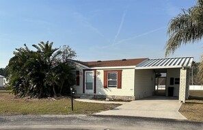 A single-story house with a front garage, a small porch, and a palm tree in the yard. - 3 Bedroom Palm Key Village Home - PK015 (Davenport)