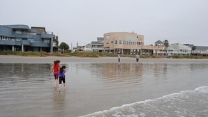 Una playa con un edificio moderno al fondo.