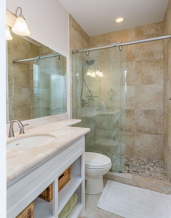 A modern bathroom with a glass-enclosed shower, a white sink, and a toilet.