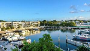 A marina with boats docked, a building with multiple floors, and a clear sky. - 406 Mariners Club - 3 bedroom elegant tri-level townhome with views of the ocean (Tavernier)