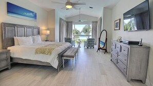 A bedroom with a bed, bedside tables, a dresser, a mirror, and a television. - 406 Mariners Club - 3 bedroom elegant tri-level townhome with views of the ocean (Tavernier)