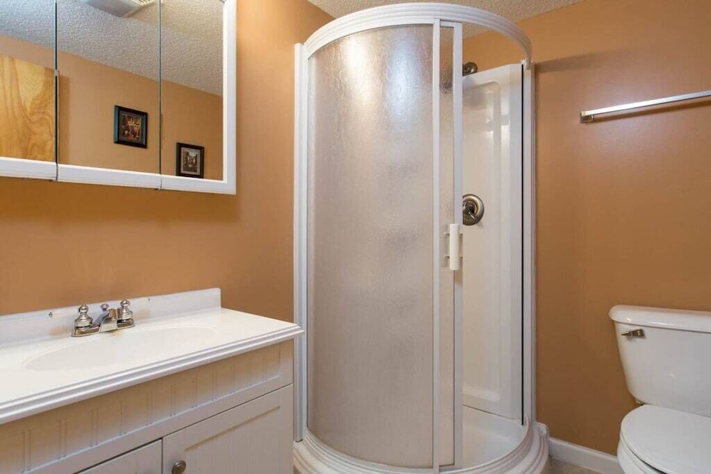 A bathroom with a shower enclosure, a sink, and a toilet.