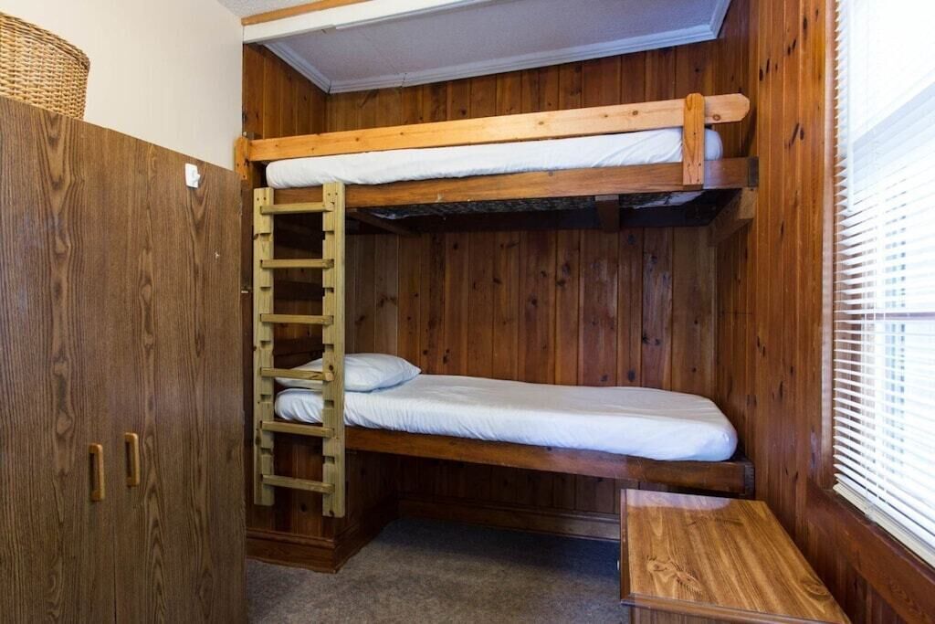 A bunk bed room with wooden walls and a ladder.