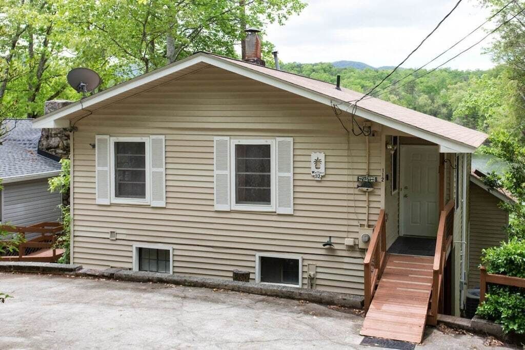 A single-story house with a front porch, a small ramp leading to the entrance, and a satellite dish on the roof.