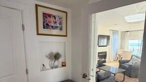 Käytävän päästä avautuu olohuone, jossa on sohva, sohvapöytä ja näkymä ulos.
