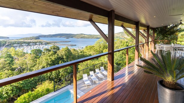 A wooden deck with a pool, overlooking a scenic landscape with hills and a body of water. - Cowries - Hamilton Island (Hamilton Island)