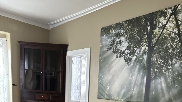 Una sala de estar con un sofá gris, una mesa de centro de madera, un tapete estampado, un cuadro grande con motivos de bosque y un aparador de madera oscura.