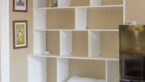 Una habitación con un mueble blanco empotrado para estanterías, un televisor de pantalla plana sobre un soporte y un cuadro en la pared.