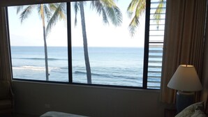 A bedroom with a large window overlooking the ocean, a bed with a patterned bedspread, a lamp, and curtains. - Spectacular OCEANFRONT! 2BR/2BA Papakea L-305. June 14 - 18th 250/nt (Kaanapali)