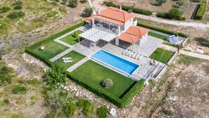 An aerial view of a property with a swimming pool, a covered patio, and a garden.