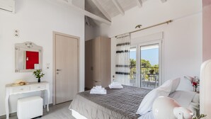 A bedroom with a bed, a bedside table, a desk, a chair, a window with curtains, and a balcony.