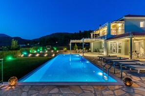 A swimming pool with a stone deck, outdoor seating, and a covered area with tables and chairs. - Luxury Villa with Private Pool in Skopelos, Ideal for Families, Aelia by Kardous (Skopelos)