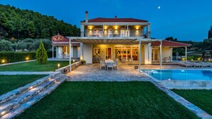 A two-story house with a swimming pool, outdoor seating, and a well-maintained garden.