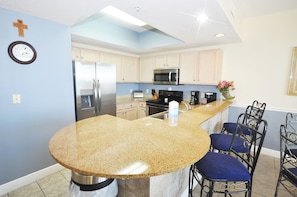 A kitchen with a granite countertop, stainless steel appliances, and blue walls.