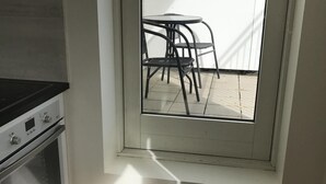 A kitchen with a built-in oven and a window overlooking a patio with outdoor furniture. - Nice Holiday Apartment, Centrally Located With Spectacular Sea And Mountain View (Akureyri)