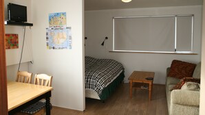 A room with a bed, a desk, a chair, a television, and a map on the wall. - Nice Holiday Apartment, Centrally Located With Spectacular Sea And Mountain View (Akureyri)