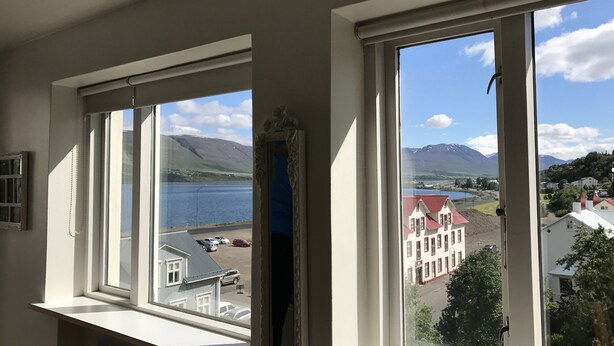 A room with two windows overlooking a lake and mountains. - Nice Holiday Apartment, Centrally Located With Spectacular Sea And Mountain View (Akureyri)