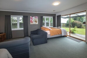 A bedroom with a bed, a sofa, and a large window with curtains. - Lounge to Lake - Water's Edge, Lake Rotorua (Ngongotaha)