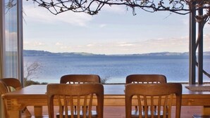 Eine Holzterrasse mit Tisch und Stühlen mit Blick auf ein Gewässer.