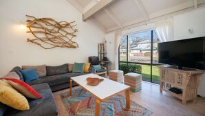 Ein modernes Wohnzimmer mit einer Couch, einem Couchtisch, einem Fernseher und einem großen Fenster.