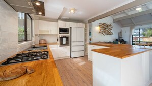 Eine moderne Küche mit weißen Schränken, einer Holz Arbeitsplatte, einem eingebauten Ofen und einem Edelstahl-Kühlschrank.