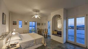 A spacious bedroom with a large bed, a ceiling fan, a desk, and a view of the sea through the sliding glass doors. - Pure White Villa: 7 Bedrooms, 16 Guests, Sea View, Aspro Chorio Village


 (Egeo)