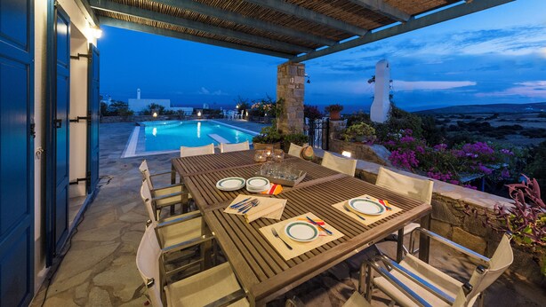 An outdoor dining area with a pool and a view of the landscape. - Pure White Villa: 7 Bedrooms, 16 Guests, Sea View, Aspro Chorio Village


 (Egeo)