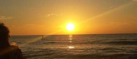 A sunset over the ocean with a person in the foreground.
