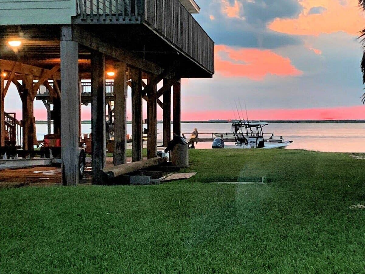 A waterfront property with a wooden deck, a boat dock, and a grassy area.