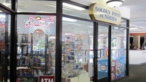 Uma loja com um anúncio da Budweiser, um caixa eletrônico e uma placa para Golden Pond Sundries.