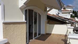 Un immeuble résidentiel doté d’un balcon, d’une porte-fenêtre coulissante et d’une terrasse carrelée.