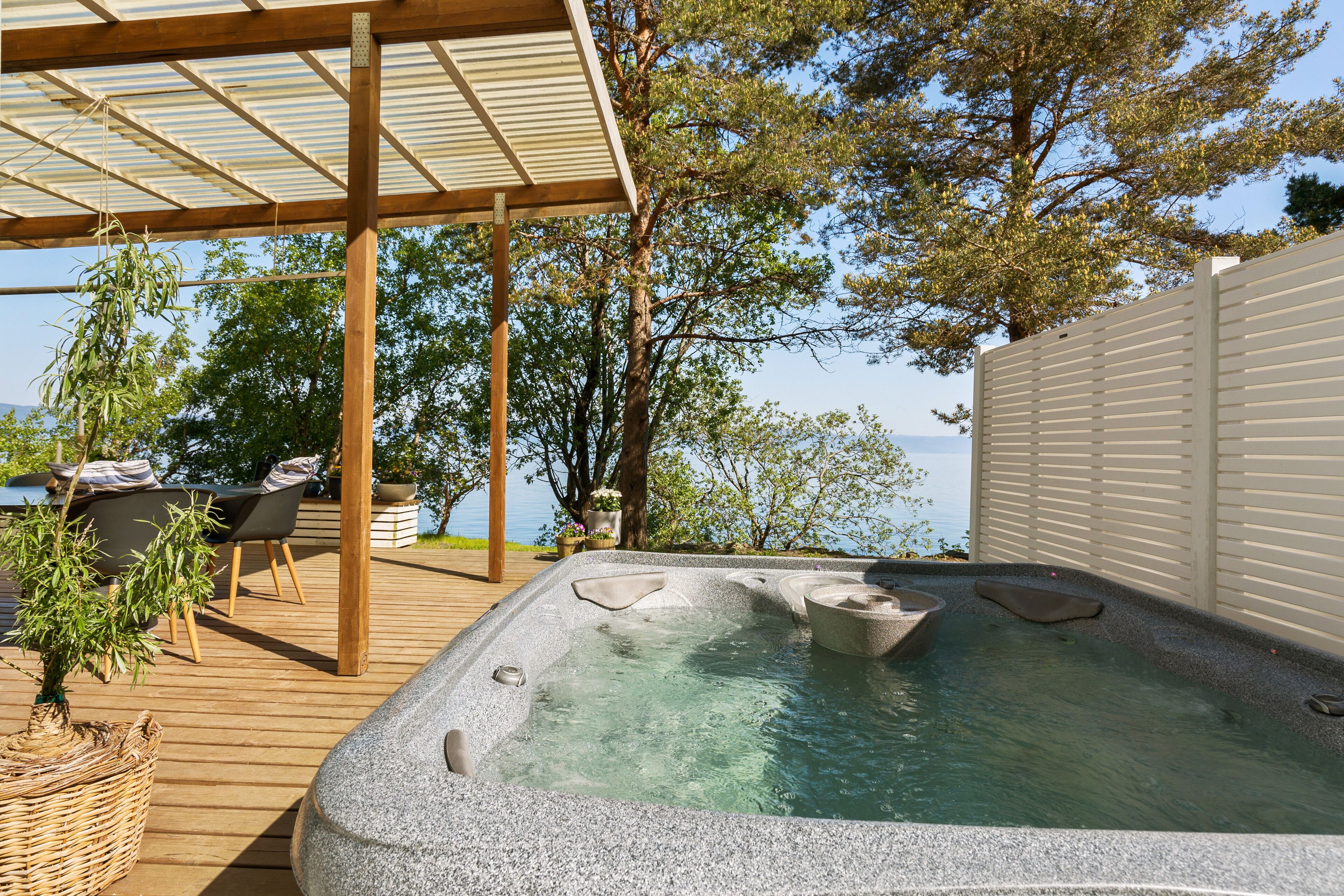 A hot tub on a wooden deck with a view of the sea.