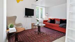 A living room with a red sofa, a round coffee table, a TV mounted on the wall, and a patterned rug. - Bungalow by The Sea (Trondheim)