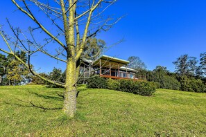 Situated on a grassy hill, this house offers a spacious balcony and a well-manicured lawn.