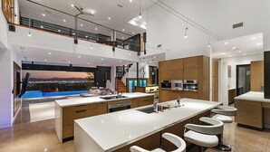 A modern kitchen with a large island, bar stools, and a view of the city at sunset.