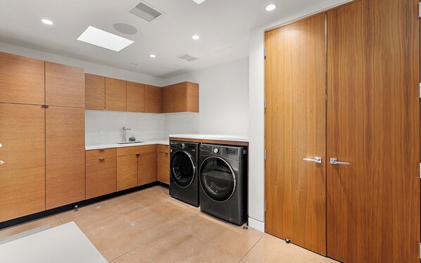 Une cuisine moderne avec des meubles en bois, un évier et deux machines à laver noires.