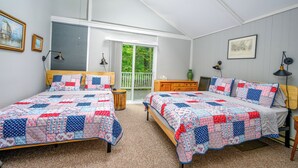 A bedroom with two beds, a window with a view of greenery, and a ceiling fan.