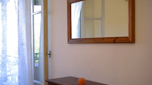 A room with a wooden dresser, a mirror on the wall, and a window with sheer curtains.