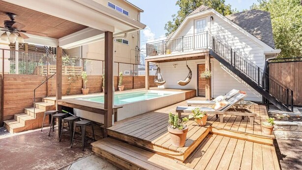 A backyard with a hot tub, wooden deck, and outdoor seating area.