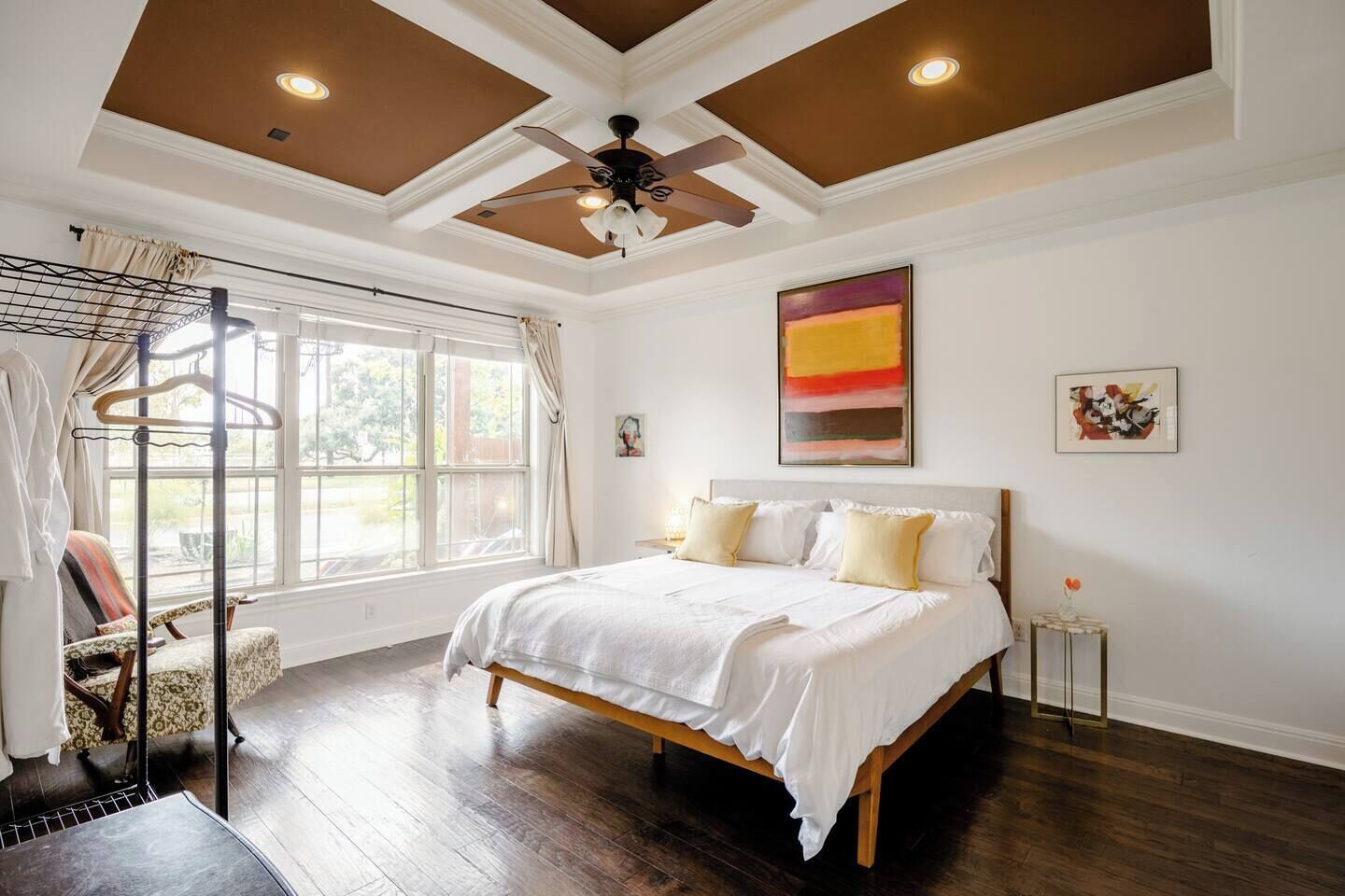 A bedroom with a large bed, a ceiling fan, and a window with curtains.