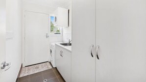 Uma cozinha compacta com máquina de lavar, pia e porta de acesso a um banheiro.