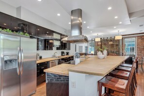 A modern kitchen with stainless steel appliances, a large island, and a brick accent wall. - Heated Pool Access | 5*Clean | Flex Cancelation (Savannah)