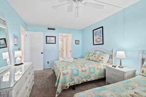 A bedroom with a bed, a nightstand, a dresser, and a mirror. There is a door leading to another room. - Remodeled! - Direct Walk Out to Beach & Pool - Pet Friendly (Flagler Beach)