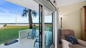A balcony with a view of the beach, a chair, a table, and a lamp. - Remodeled! - Direct Walk Out to Beach & Pool - Pet Friendly  (Flagler Beach)