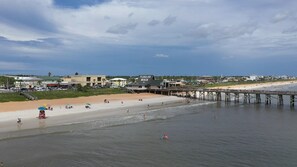 A beach with a pier, beach umbrellas, and a lifeguard tower. - Remodeled! - Direct Walk Out to Beach & Pool - Pet Friendly  (Flagler Beach)