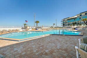 A swimming pool with a tiled deck, surrounded by lounge chairs and a white fence. - Remodeled! - Direct Walk Out to Beach & Pool - Pet Friendly (Flagler Beach)