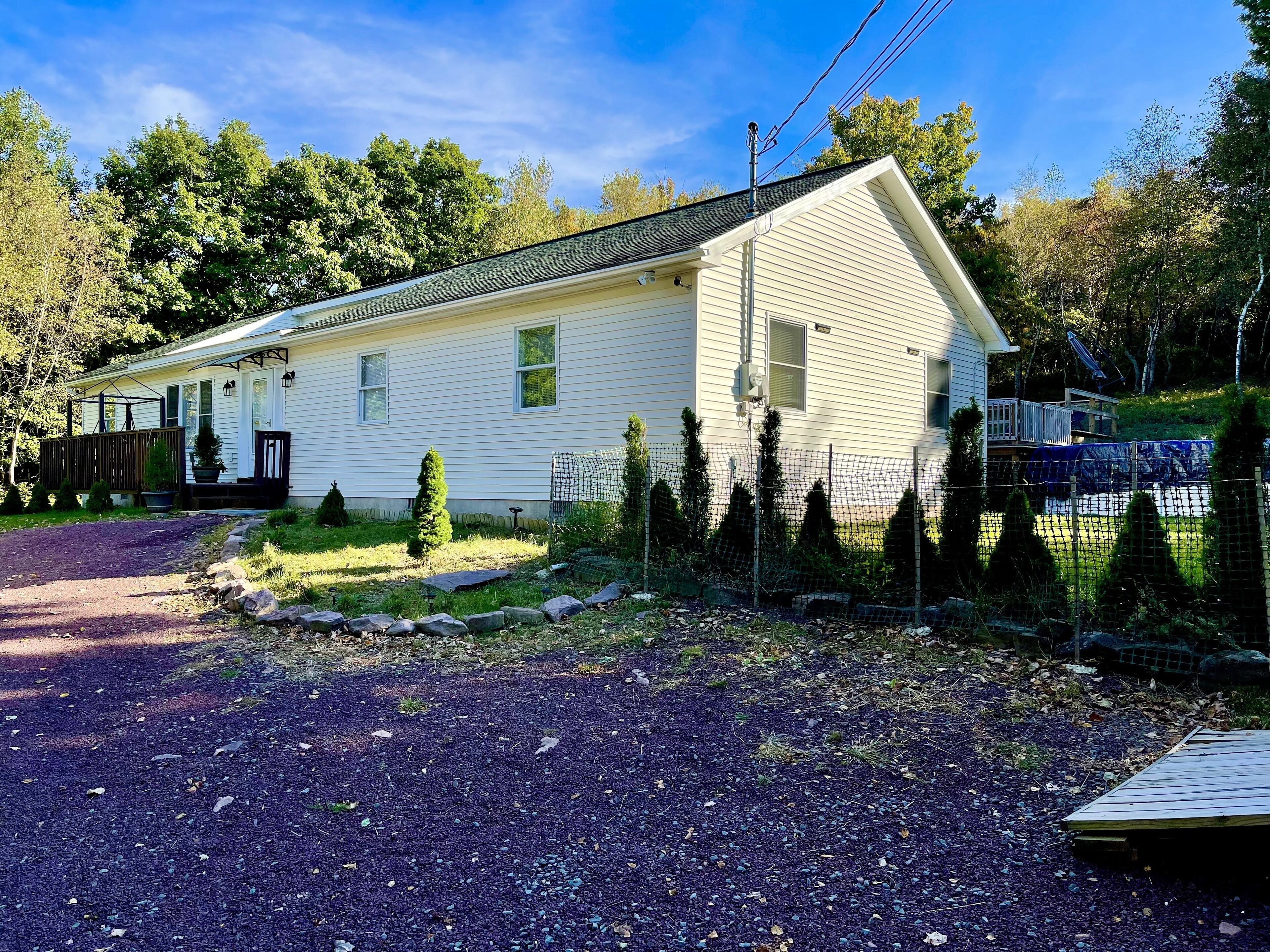 A single-story house with a sloped roof, a front porch, and a small deck.