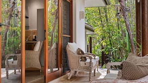 A room with wicker furniture, a glass door leading to a garden, and a view of lush greenery. - "La Cabane" - Private Pool (Copacabana)