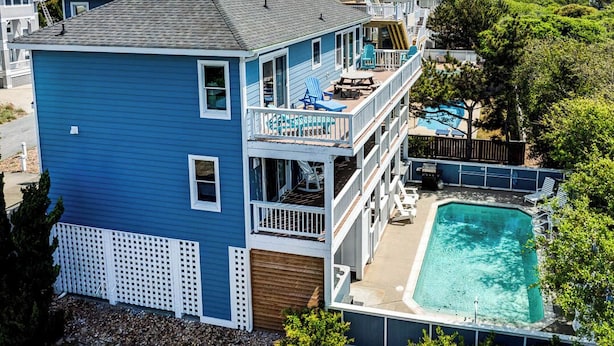 Een tweelaags huis met een zwembad, een terras en uitzicht op zee.